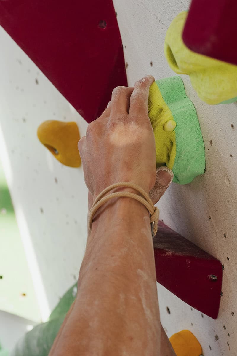 Bouldergriff wird mit zwei Händen festgehalten