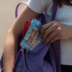 Ein Mädchen nimmt ihren ZVV-Ferienpass aus der Umhängetasche